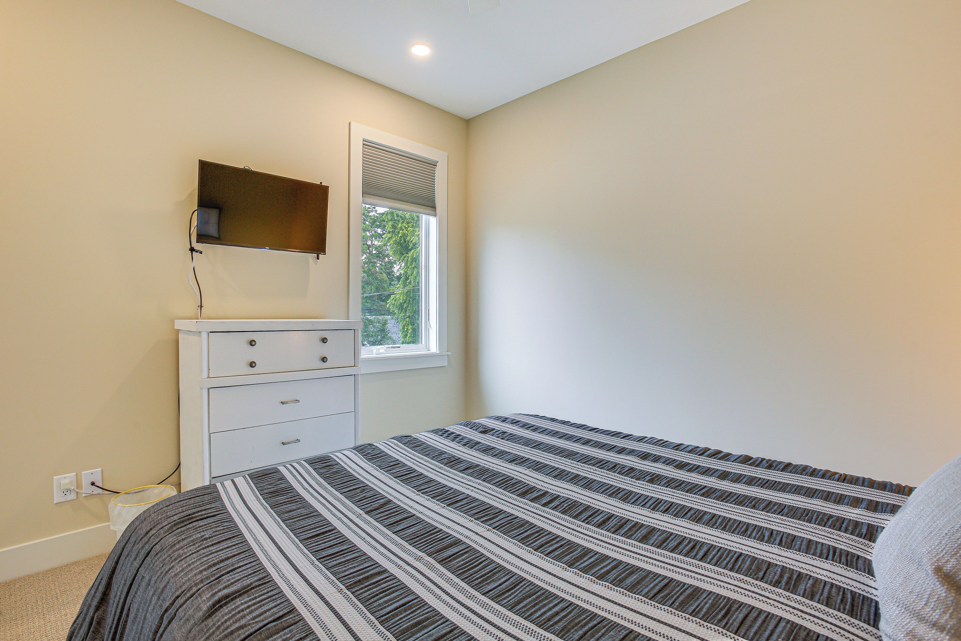 A bedroom with a bed, a dresser, a mirror, and a window.