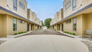 Une rangée d’immeubles d’appartements modernes, de couleur beige, avec une allée centrale menant à un garage.