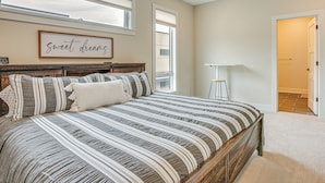 Une chambre à coucher avec un grand lit, une tête de lit, une table de chevet et un panneau décoratif fixé au mur.