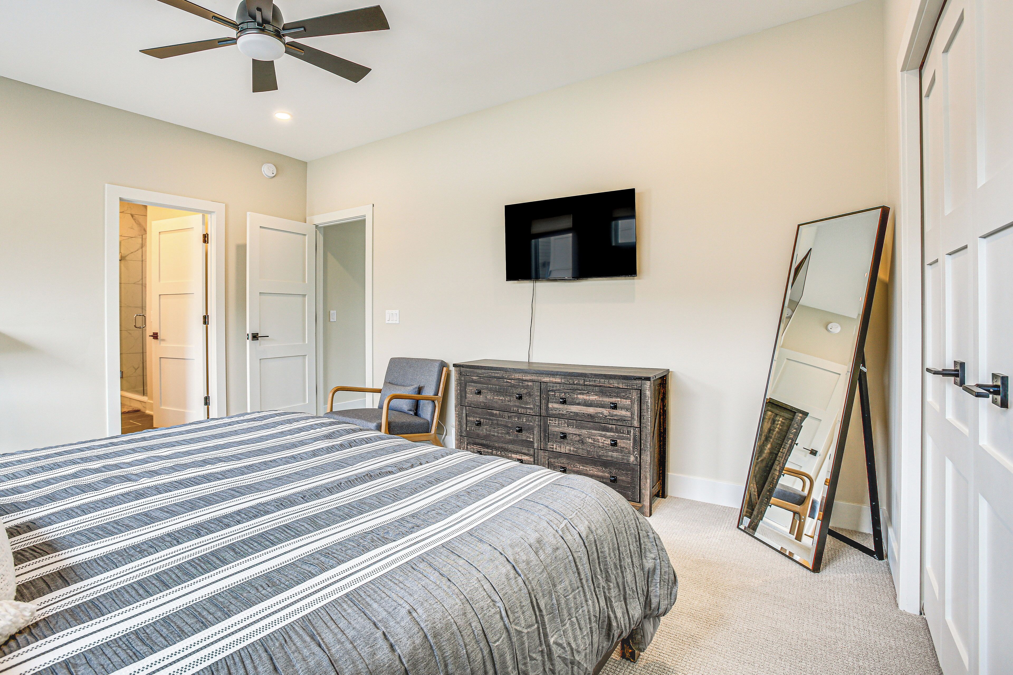 A bedroom with a bed, a dresser, a television, and a mirror.