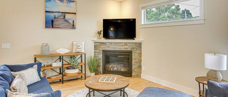 A living room with a fireplace, a television, and a view of the outdoors through a window.