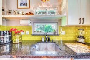 A kitchen with a stainless steel sink, a window with a view of greenery, a blender, and a knife block. - Rainforest Retreat w/ Hot Tub: Mins to Nat'l Park! (Volcano)