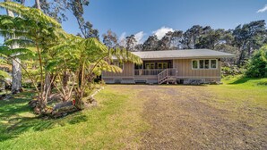 A single-story house with a porch, surrounded by lush greenery and trees. - Rainforest Retreat w/ Hot Tub: Mins to Nat'l Park! (Volcano)