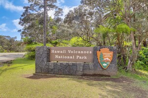 Señal de Hawaii Volcanoes National Park, con un muro de piedra y vegetación exuberante.