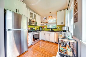 A modern kitchen with stainless steel appliances, white cabinets, and a wooden floor. - Rainforest Retreat w/ Hot Tub: Mins to Nat'l Park! (Volcano)