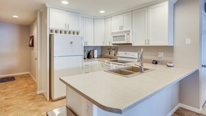 A modern kitchen with white cabinetry, a built-in microwave, and a stainless steel sink.