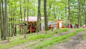 Une cabane dotée d’une terrasse en bois, entourée d’une forêt dense.