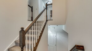 Una escalera con barandillas de madera y un rellano alfombrado.