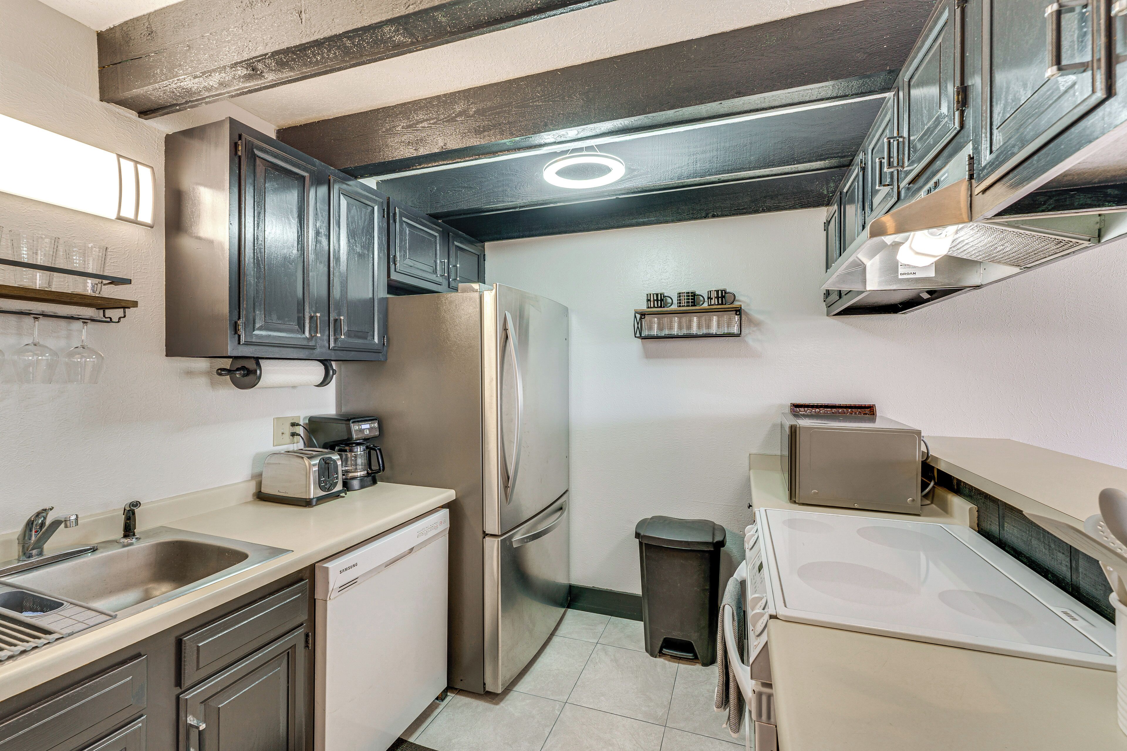 A compact kitchen with a stainless steel refrigerator, a toaster, and a sink.