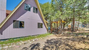 Un edificio rosa con un tetto triangolare, immerso tra alberi e un vialetto sterrato.