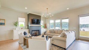 A spacious living room with a fireplace, a large sofa, and a television. - Waterfront Alexander City Home w/ Private Dock! (Alexander City)