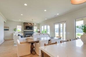 Amplia sala de estar con un gran comedor, asientos cómodos, chimenea y ventanas grandes que ofrecen vistas.
