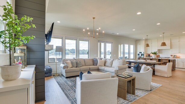 A spacious living room with a large sectional sofa, a coffee table, and a view of the outdoors through large windows. - Waterfront Alexander City Home w/ Private Dock! (Alexander City)