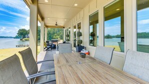 A covered patio with a wooden table and chairs, overlooking a lake. - Waterfront Alexander City Home w/ Private Dock! (Alexander City)
