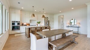 A spacious kitchen with white cabinetry, a wooden dining table, and a large island with seating. - Waterfront Alexander City Home w/ Private Dock! (Alexander City)
