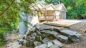 A house with a porch, a stone retaining wall, and a forested area. - Black Mountain Hideaway w/ Hot Tub & Pool Table! (Black Mountain)