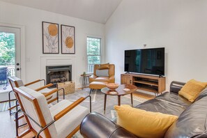 A modern living room with a fireplace, leather sofa, armchairs, and a flat-screen TV. - Black Mountain Hideaway w/ Hot Tub & Pool Table! (Black Mountain)