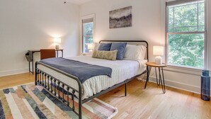 A bedroom with a bed, bedside tables, a rug, and a window with a view of trees. - Black Mountain Hideaway w/ Hot Tub & Pool Table! (Black Mountain)