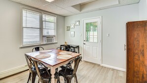 Un coin repas avec une table en bois, des chaises noires et une porte blanche.