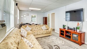 Un salon comprenant un canapé d’angle, un téléviseur à écran plat et un meuble de rangement en bois.