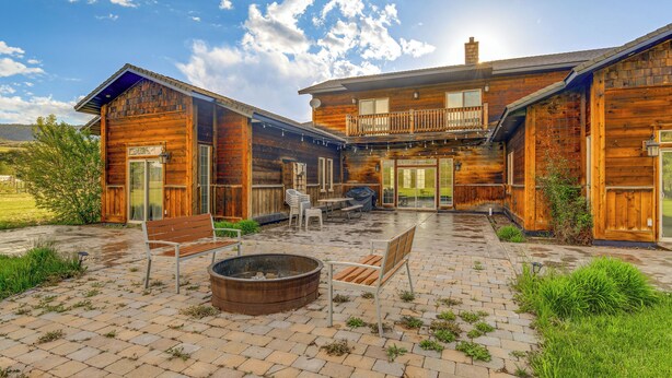 A wooden cabin with a patio area featuring a fire pit, outdoor seating, and a covered barbecue area. - Spacious Afton Home: Patio, Grill & Mountain Views (Afton)