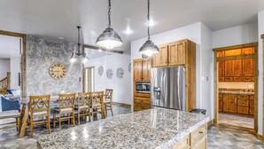 A kitchen with granite countertops, wooden cabinets, stainless steel appliances, and pendant lighting. - Spacious Afton Home: Patio, Grill & Mountain Views (Afton)