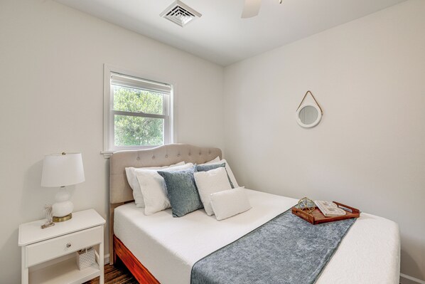 A neatly arranged bedroom with a bed, bedside table, lamp, and a window. - Waterfront Getaway w/ Private Docks, Fire Pit (Tuckerton)