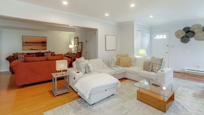 A modern living room with a sectional sofa, a glass coffee table, and a white armchair. - Somerset Home w/ Large Yard Near Parks & Trails (Somerset)