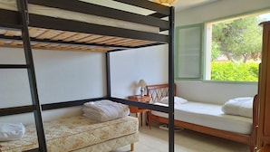 Ein Schlafraum mit Etagenbett, Fenster, Nachttisch und einer Couch.