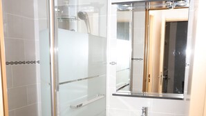 Une salle de bain moderne avec une douche à parois de verre, un lavabo blanc et un miroir au-dessus.