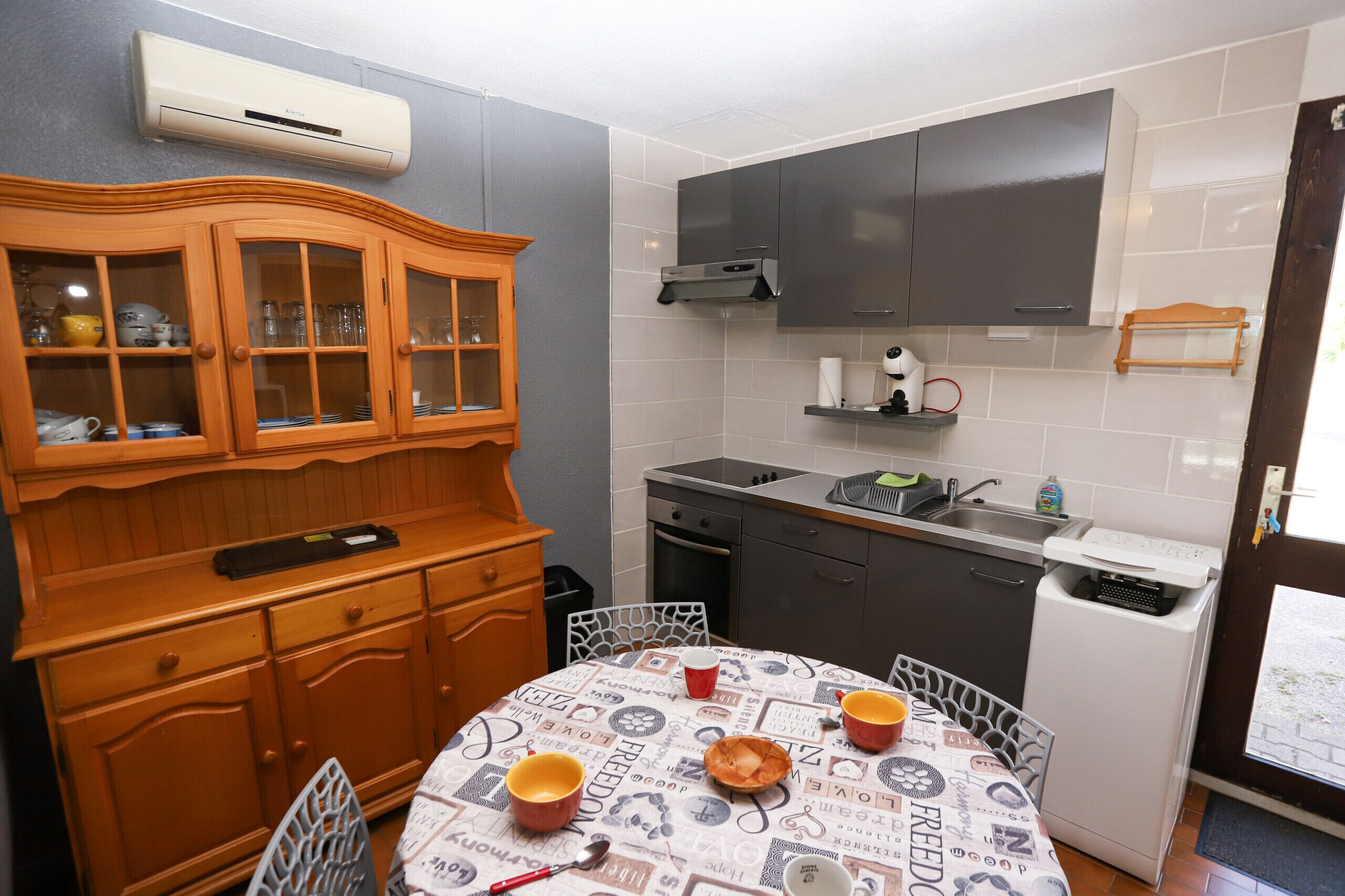 Eine kompakte Küche mit Esstisch, Holzschrank und eingebautem Backofen.