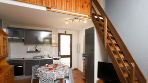Une cuisine compacte avec un coin repas, un escalier en bois et un téléviseur.