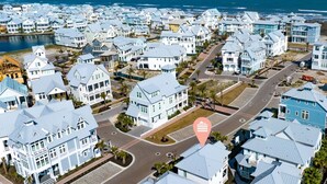 A coastal residential area with houses featuring light blue and white exteriors, arranged in a grid pattern with a road in the center. - Bird Feather 160tai - C (Port Aransas)
