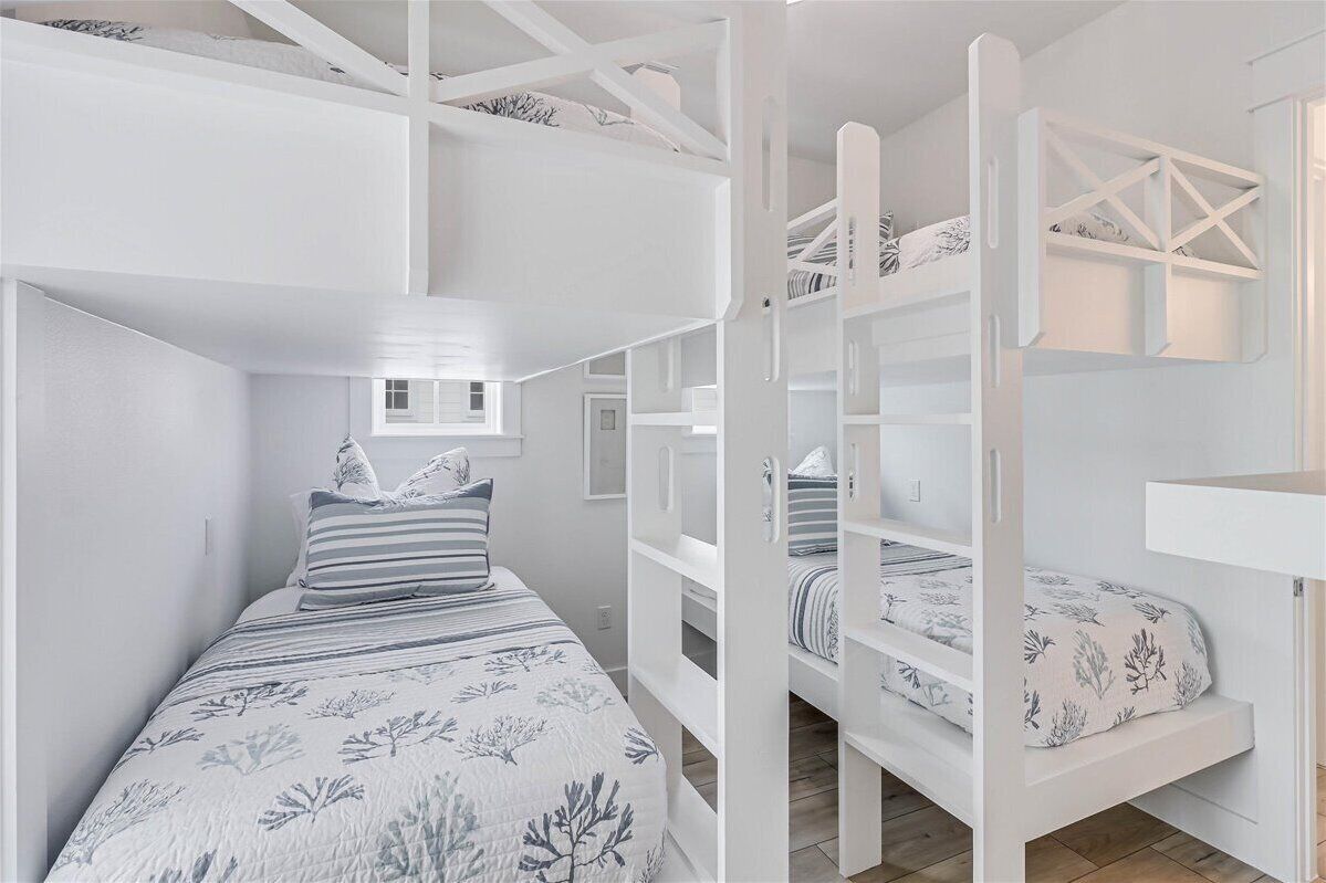 A room with a bunk bed, a desk, and a window.