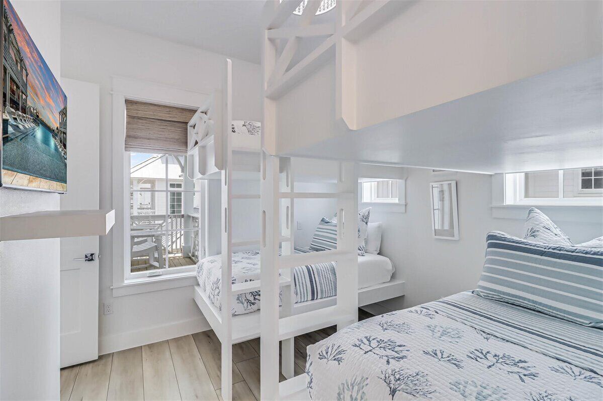 A room with bunk beds, a window with a view, and a door.