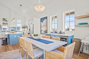 Uma cozinha espaçosa com uma ilha grande, armários brancos e vista para o exterior.