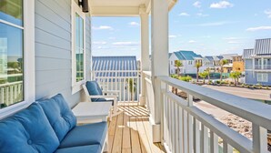 A covered porch with a white railing, a blue sofa, and a table. - The Seaward 217 STA (Port Aransas)
