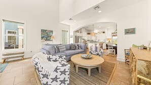 Ein geräumiges Wohnzimmer mit einer Couch, einem runden Couchtisch und einem Essbereich mit einem Holztisch.