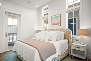 Un dormitorio con cama, mesita de noche, ventana y puerta.
