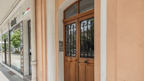 A building facade with a large wooden door and a window with decorative ironwork. - T3 Appartement au centre ville (Annecy)