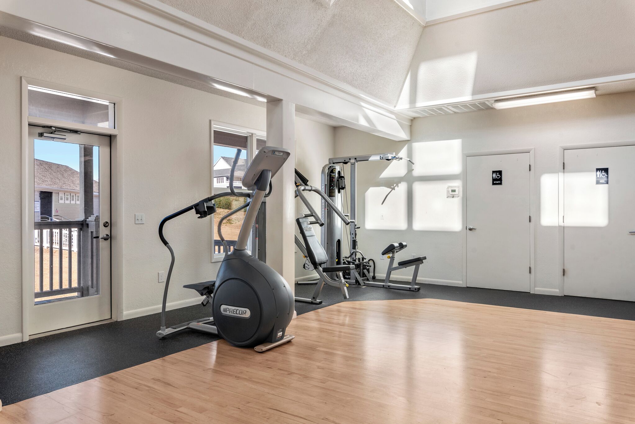 A gym with cardio equipment, weight machines, and a mirror.