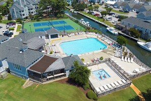 A residential area with a swimming pool, tennis courts, and a dock with boats.