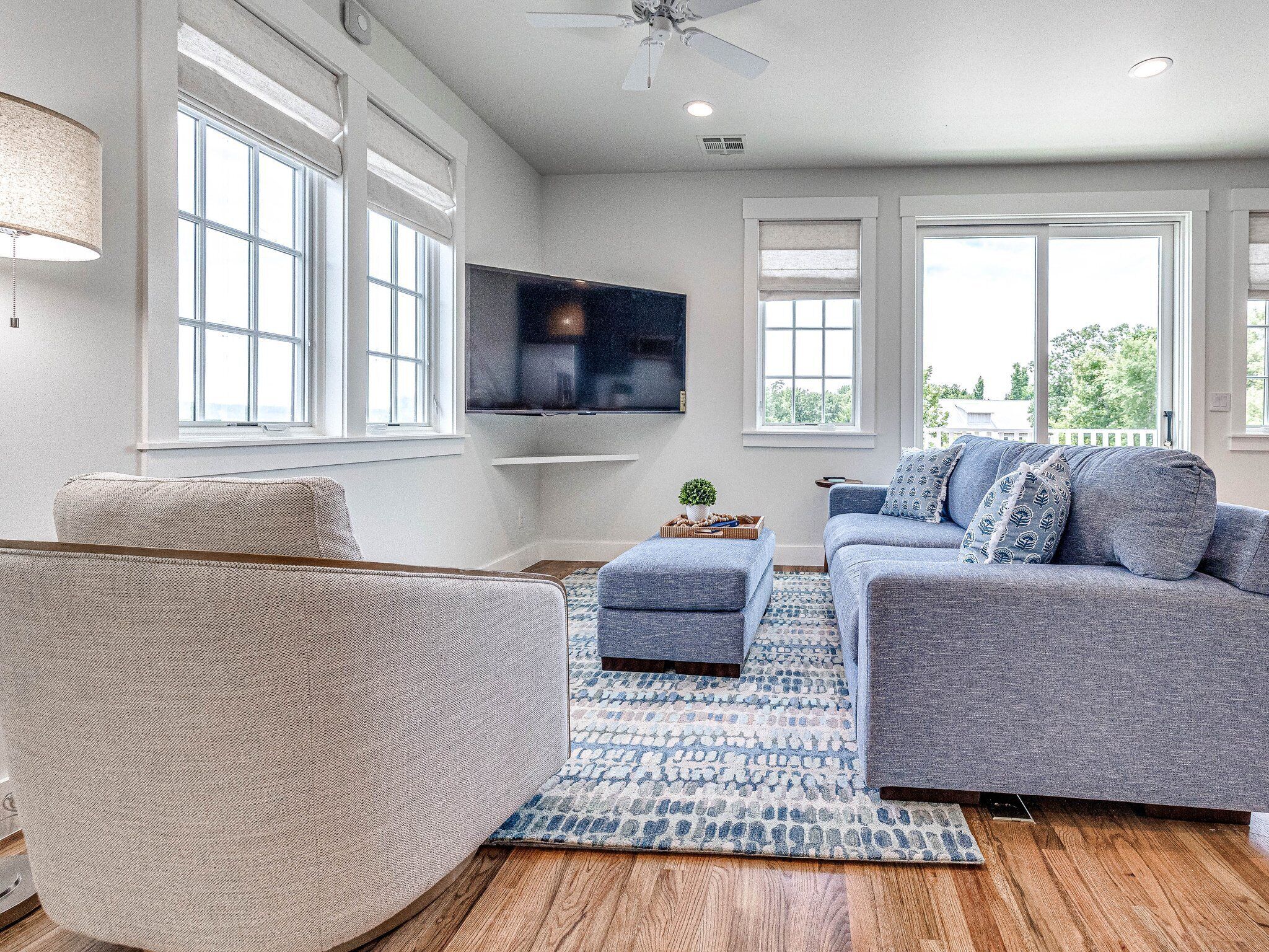 Una sala de estar moderna con un sofá gris, un sillón beige y un tapete azul estampado.