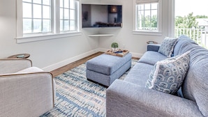 A living room with a grey sofa set, a flat-screen TV mounted on the wall, and a patterned rug. - Carlton Landing-Carriage House (Carlton Landing)