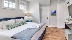 A bedroom with a bed, nightstand, and a painting on the wall. - Carlton Landing-Carriage House (Carlton Landing)