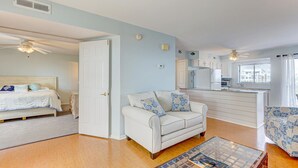 A compact living space with a bed, a sofa, a coffee table, and a kitchenette.