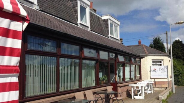 A building with a large windowed front, outdoor seating area with tables and chairs, and a signboard. - Ardenlea House Hotel B&B (Aberdeen)