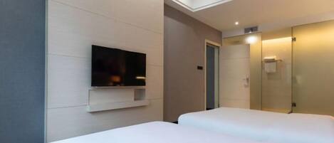 A hotel room with two beds, a flat-screen TV mounted on the wall, and a mirror on the wall.