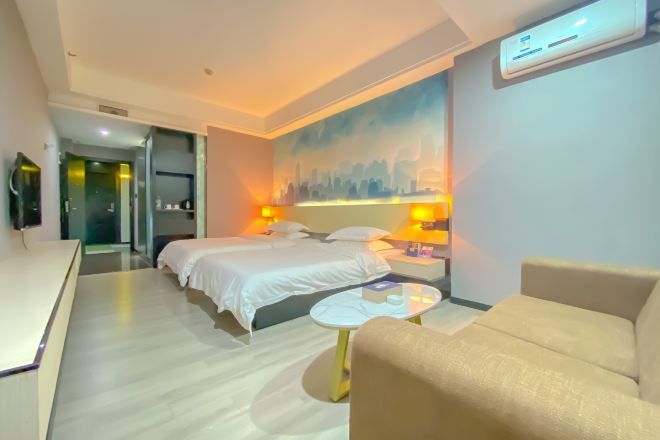 A hotel room with a bed, bedside tables, a desk, a chair, and a painting on the wall.