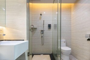 A modern bathroom with a glass-enclosed shower, a white toilet, and a white sink. - Caiyang Hotel (Haifeng)